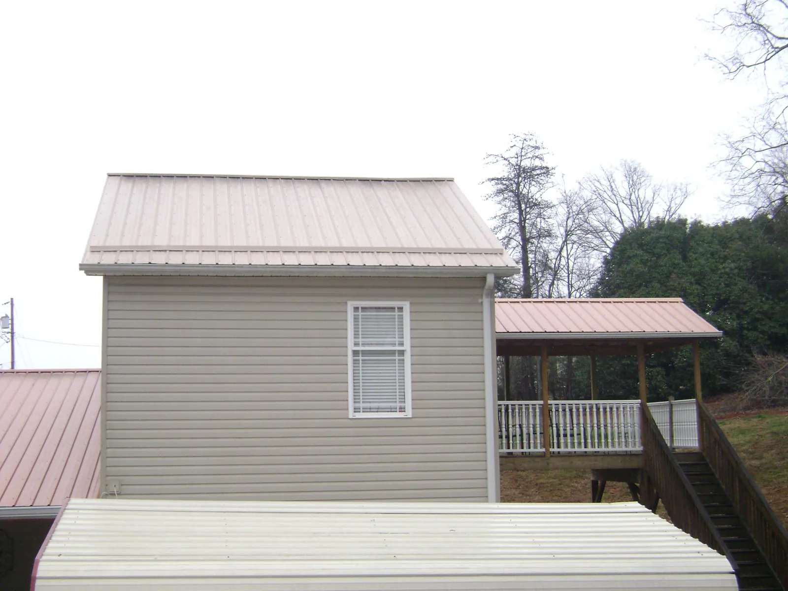 Tan metal roofs on a two story addition and attached porch, from a Roof Replacement job in Seymour